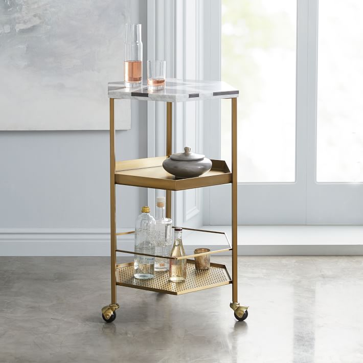 Look for a small-scale bar cart, and one on wheels, like this one from West Elm that can be moved around and utilized as a side table as well as a display piece for your booze.