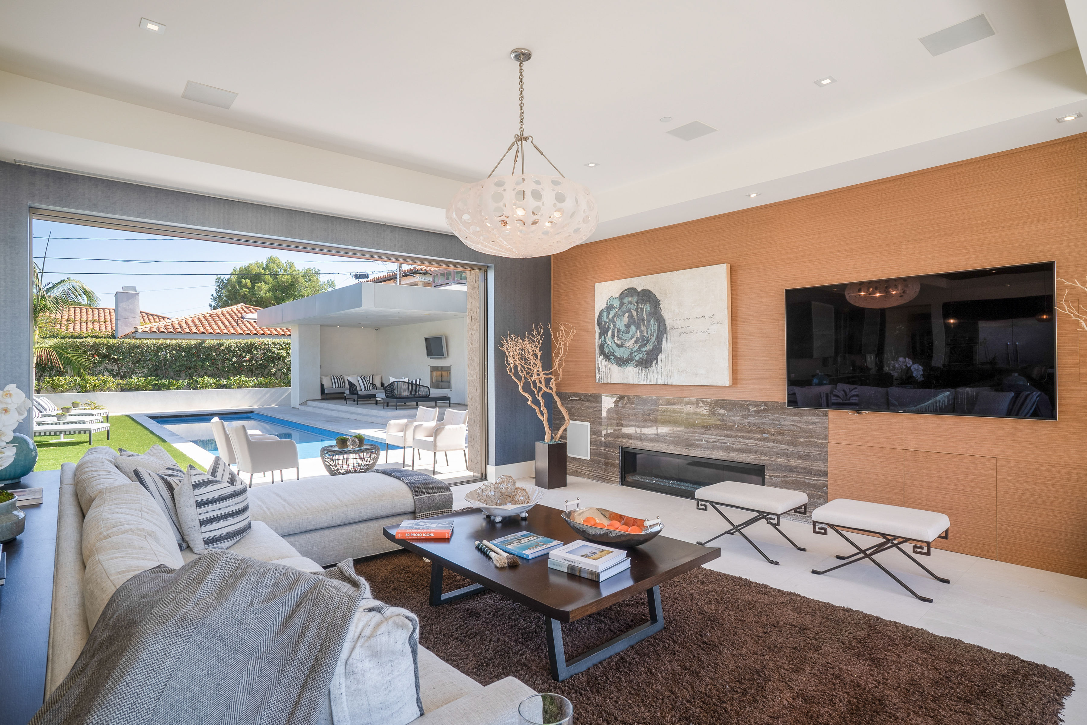 Manhattan Beach Living Room features full wall sliding window system for indoor outdoor feel, organic shape lighting fixtures, and luxury architectural details